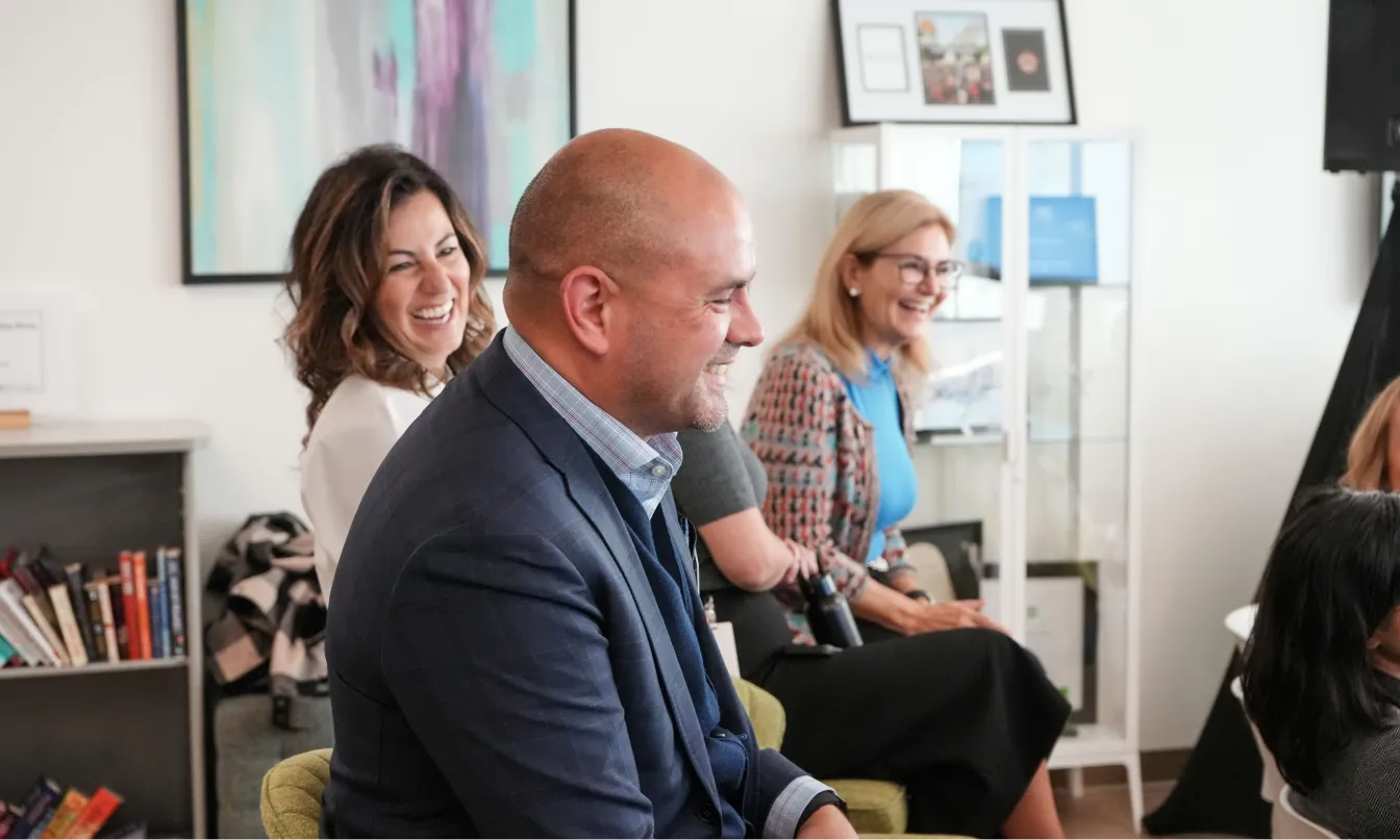 Members of the executive team sitting in chairs, all laughing and engaging with one another.